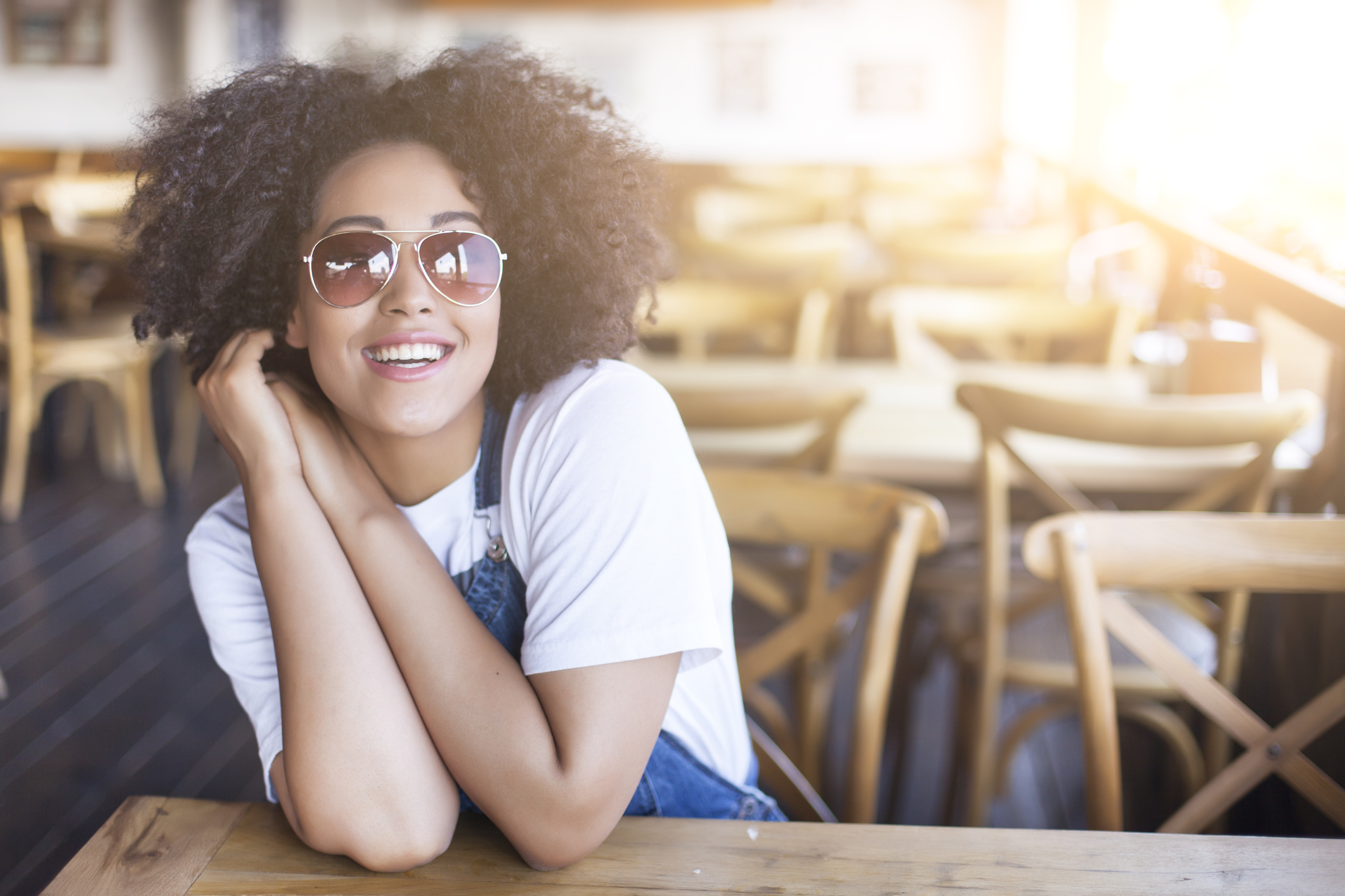 Smiling african woman sitting in sunny cafe