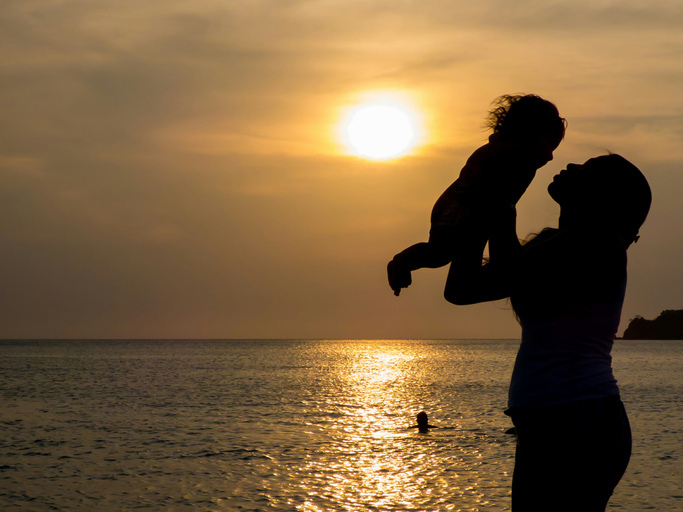 Silhouette Of Female Holding Little Girl At Sunset Sun Reflection In Sea Surface