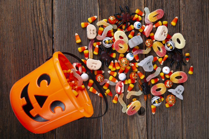 Halloween Jack o Lantern pail with bottom border of spilling candy over brown wood