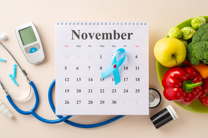 Diabetes Awareness Month appointment for a medical exam. Overhead shot of calendar featuring diabetes symbol, glucometer, needles, strips pack, stethoscope, healthy meal on a soft beige surface