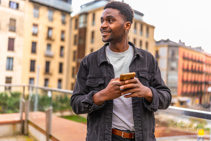 Man sending a message using smartphone standing int the city